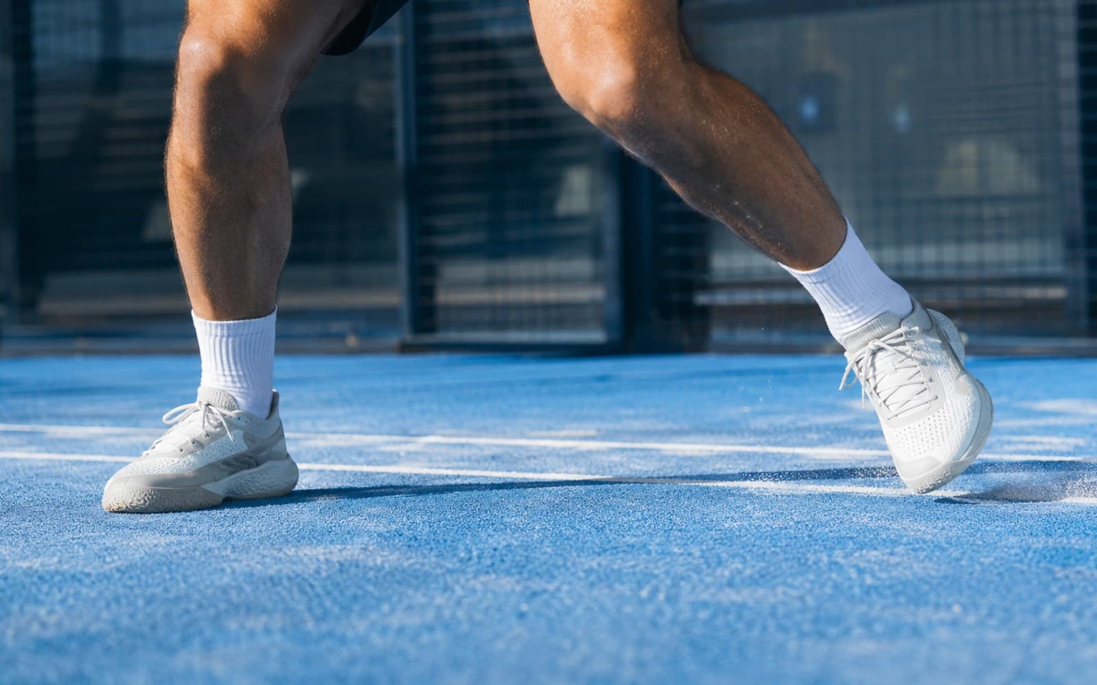 Benen en courtschoenen in beweging op een padelbaan